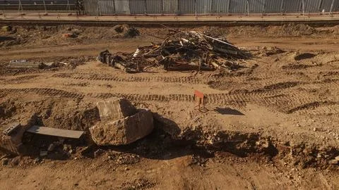 A large rock sits in a dirt construction site with debris and tire tracks Stock Photos