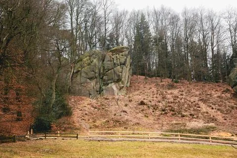 A large rock sits on a hillside next to a fence in Germany Stock Photos