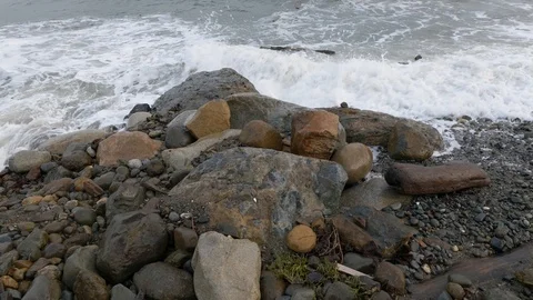 Large rocks on beach with big waves during storm. Slow tilt up in slow motion. Stock Footage 121697154