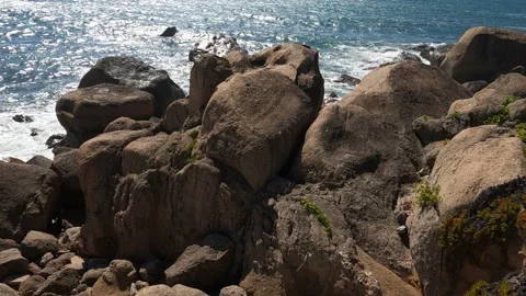 Large rocks being shaken by waves on the beach on a summer day Stock Footage 282255335
