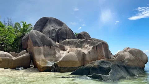Large rocks by the clear water at a beach in Seychelles Stock Footage 345729138