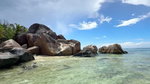 Large rocks by the clear water at a beach in Seychelles Stock Footage 345729144