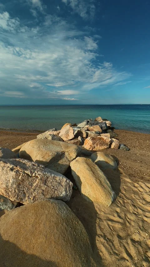 Large rocks line shore, casting soft shadows. Nikiti, Greece. Vertical Stock Footage 339025569