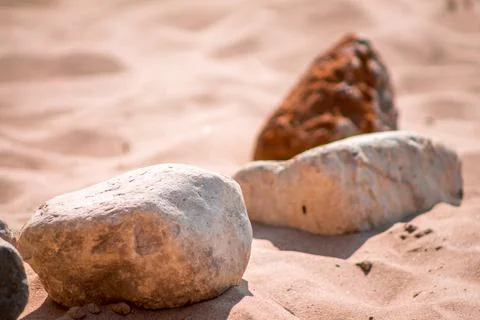 Large rocks lined up in the sand at a beach Stock Photos