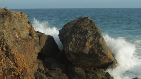 Large rocks by ocean. Waves crashing into rocky beach cu A Stock Footage 102402022