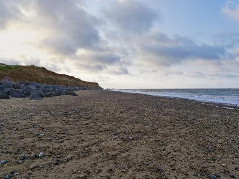 Large rocks protect the slowly eroding cliffs of Happisburgh beach Stockfoto's