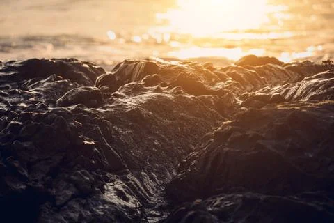 A large rocks surrounded by waves of the ocean Stock Photos