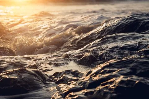 A large rocks surrounded by waves of the ocean Stock Photos