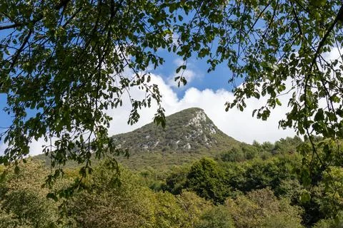Large rocky mountain range on Lake Garda under a partly cloudy blue sky, show Stock Photos