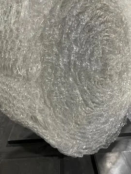 Large roll of bubble wrap placed on its side on a black tray. Transparent Stock Photos