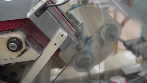 Large roll of printed red packaging film unwinding through guide rollers on a Stock Footage 342319407