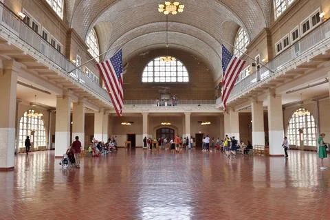 A large room with a flag hanging from the ceiling in Ellis Island Stock Photos