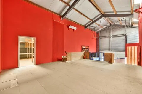A large room with a red wall and concrete floors Stock Photos