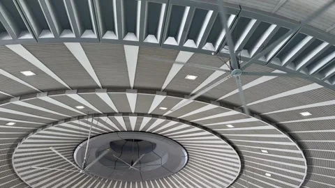 Large rotating ceiling fan installed in a spacious public hall. Stock Footage 345260289