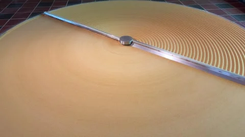 A large rotating orange disk creates concentric circular lines on a platform.  Vídeos de archivo 334580589
