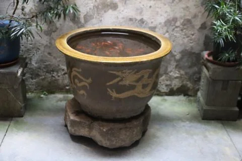 A large, round, brown ceramic pot with gold dragon patterns on the rim, fil.. Stock Photos