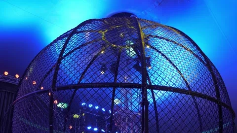A large round cage for motorcycle stunts in a circus with multicolored light. Stock Footage 311798187