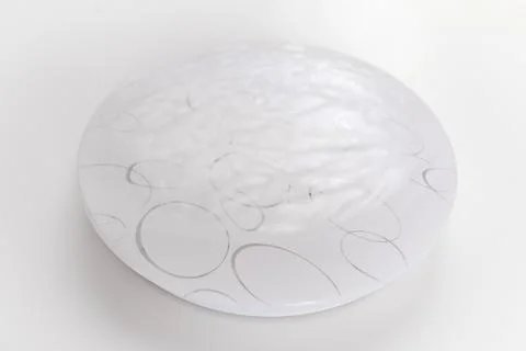 Large round ceiling lamp with a pattern on a white surface. Stock Photos