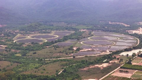 Large round solar panel installation in hilly terrain near water and forest Stock Footage 309182151