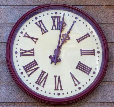 Large round wall clock on the granite facade of the house. Stock Photos