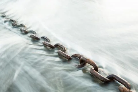 Large rusted chain in waves of the ocean Stock Photos