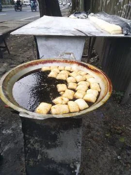 A large, rustic pan filled with oil cook some tofu Stock Photos