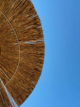 A large rustic straw parasol seen from below with bright blue sky Stock Photos