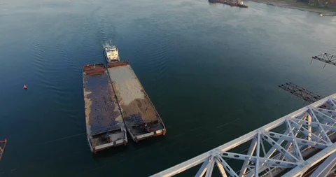 Large rusty barge floats down river under railway bridge, aerial shot, drone fly Stock Footage 128385010
