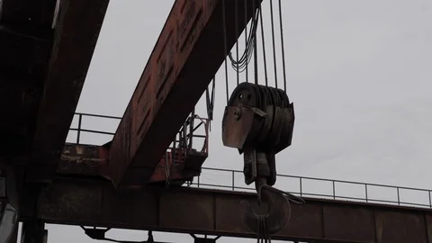 Large rusty crane hook on old black ropes and brown supports Stock Footage 115254155