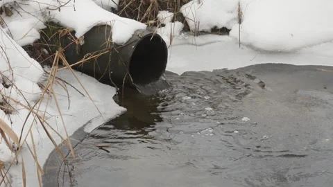 Large rusty metal culvert pipe discharges water into ditch with sound Stock Footage 329168650