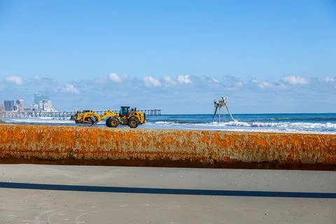 Large rusty pipe above wet sand on a beach near the ocean Stock Photos