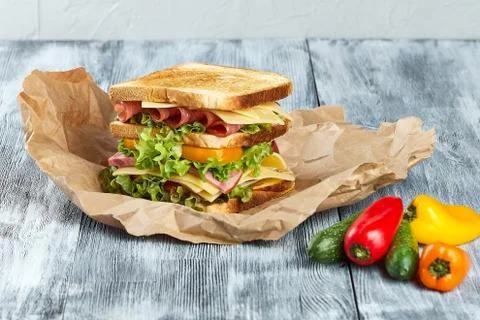 A large sandwich on toasted fried bread, with green salad leaves, with red and y Stock Photos