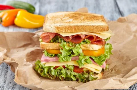 A large sandwich on toasted fried bread, with green salad leaves, with red and y Stock Photos