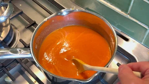Large saucepan of fresh roasted tomato and red pepper soup being stirred Stock Footage 341155383