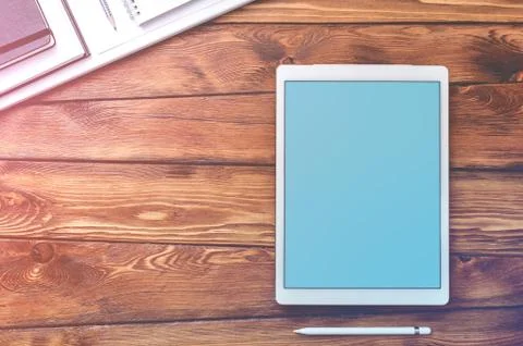 Large screen tablet device on a wooden desktop, top view. Stock Photos