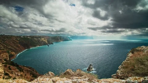 A large sea bay surrounded by a steep rocky shore, on the water a shadow of Stock Footage 223048981