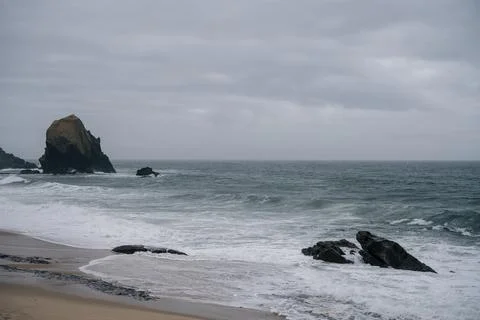 Large sea stack rising from waves on overcast day in Santa Cruz Portugal Foto stock