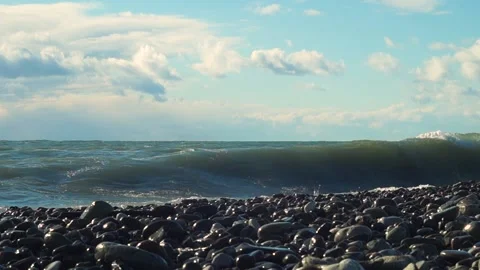 A large sea wave hits the rocks on the beach, a blue sky with fragments Video stock 169810322
