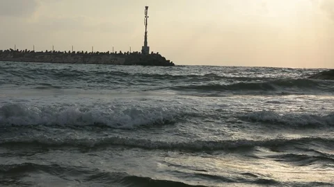 Large sea waves with splashes of foam and water on the beach with yacht port Видео 93555855
