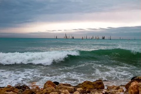 Large sea waves with splashes of foam and water on the beach and a sailing re Stock Photos