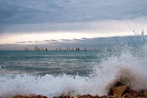 Large sea waves with splashes of foam and water on the beach and a sailing re Stock Photos