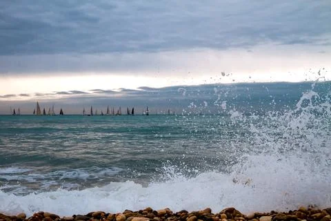 Large sea waves with splashes of foam and water on the beach and a sailing re Stock Photos