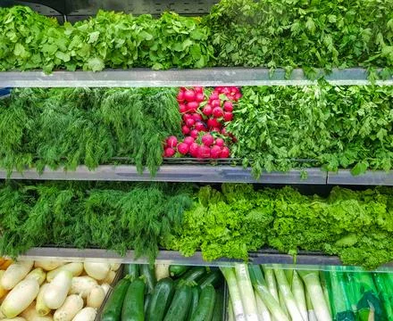 A large selection of fresh herbs and vegetables on the counter. Green dill, red Stock Photos