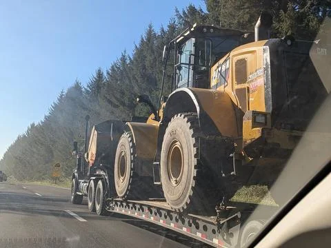 Large semi truck pulls massive yellow bulldozer on flatbed Stock Photos