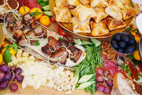 A large served table with salads, vegetables and barbecue, treats and snacks Stock Photos