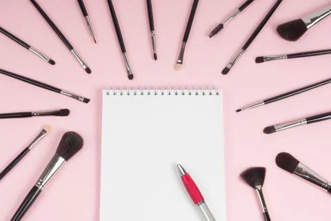 Large set of makeup brushes with a notebook and pen mock-up on a pink backgro Stock-Fotos