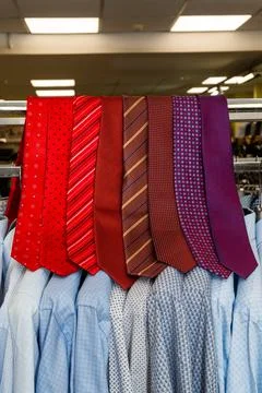 A large set of red, maroon, and purple ties lie on a crossbar. Beautifully Stock Photos