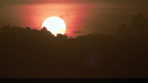 Large Setting Sun Emerging Behind Dramatic Tropical Clouds Over Open Water Stock-Footage 342695962