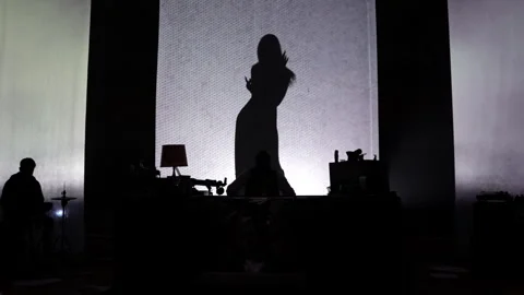 A large shadow of a dancing girl in a long dress on stage. Twilight. Stock Footage 241824806