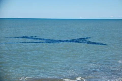 Large Shadow of Flying Airplane Cast on Turquoise Sea Water Surface near Coast Stock Photos